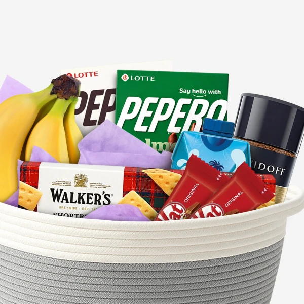 Gift basket with bananas, Pepero snacks, Walker's shortbread, KitKats, and coffee.