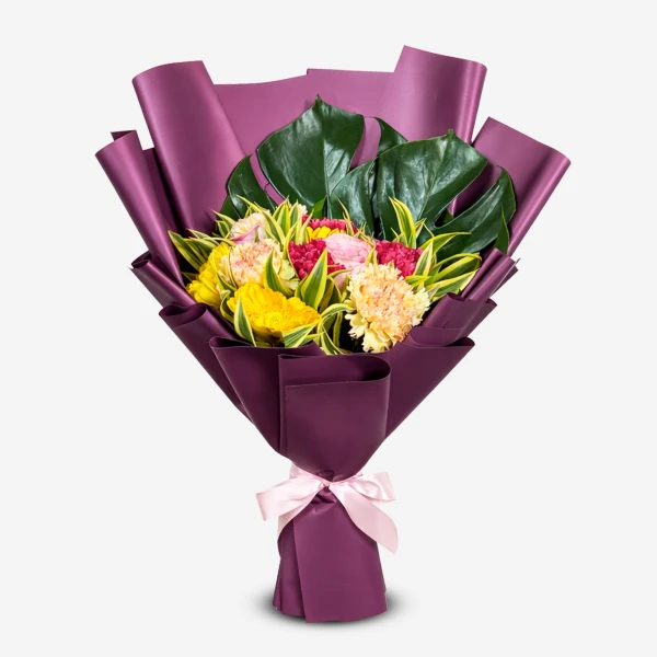 A bouquet of yellow, pink, and fuchsia flowers with green monstera leaves, wrapped in purple paper and tied with a pink ribbon.
