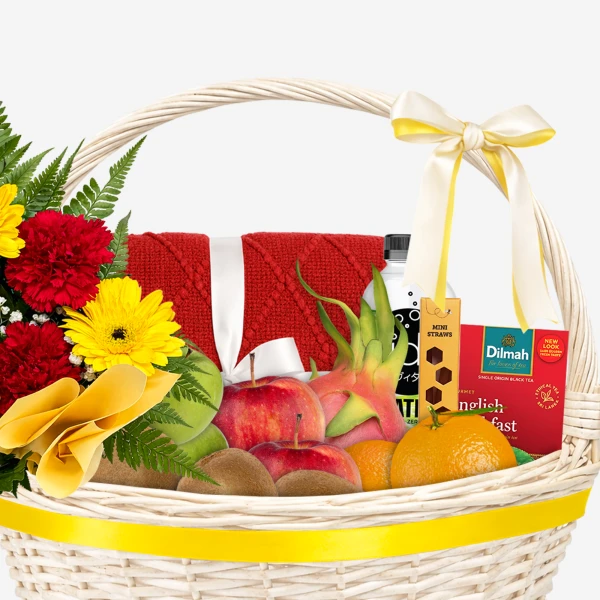 Gift basket with fruit, flowers, tea, and a towel, tied with a yellow bow.
