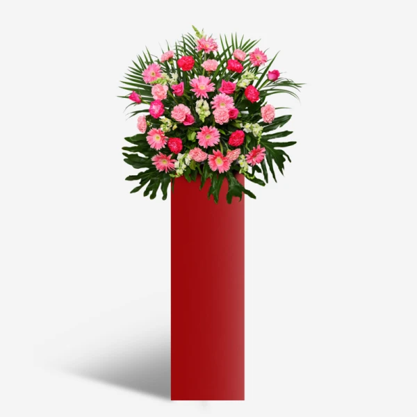 A tall red stand with a large bouquet of pink and fuchsia flowers and green foliage.