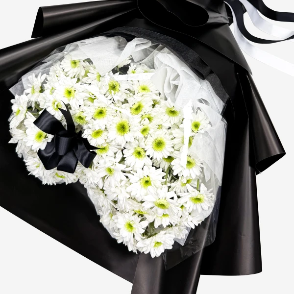 White chrysanthemums in a bouquet, wrapped in black paper with a black ribbon.