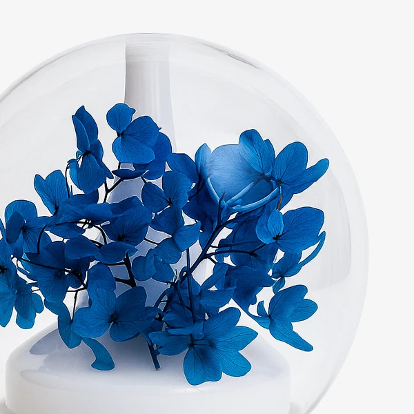 Blue hydrangea petals inside a clear glass dome diffuser with a white base.