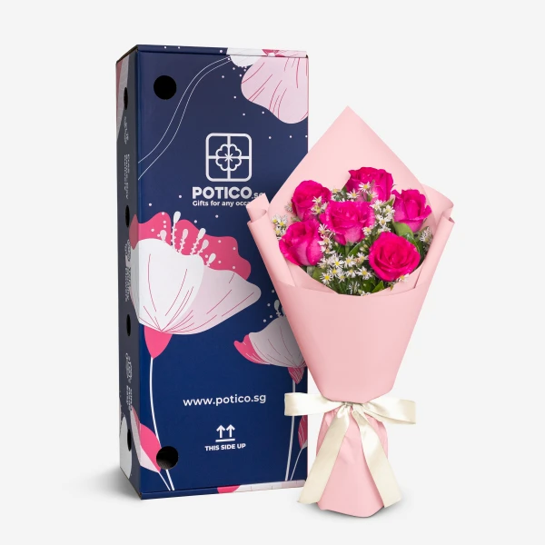 A bouquet of six pink roses in pink paper with a white bow, next to a dark blue box with floral designs.
