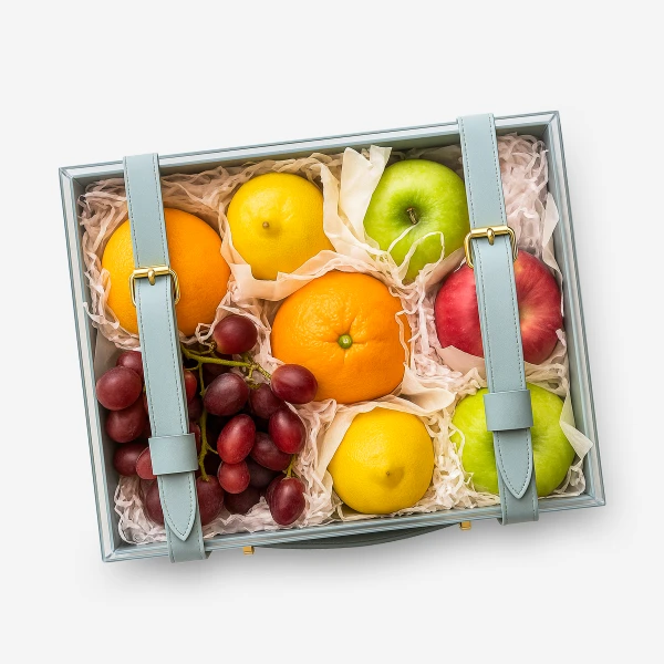 A fruit gift box with grapes, red apple, oranges, lemons, and green apples.