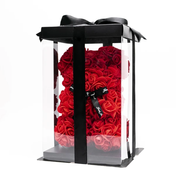 Red rose teddy bear in a clear display box with a black lid and ribbon.