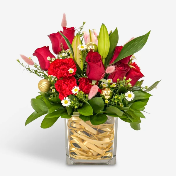 A vibrant bouquet of red roses and carnations in a glass vase adorned with gold ribbon.