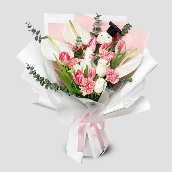 Bouquet of white anthuriums, pink and white tulips, pink carnations, and eucalyptus with a graduation charm.