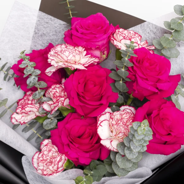 Pink roses and red-and-white carnations with eucalyptus in a bouquet.