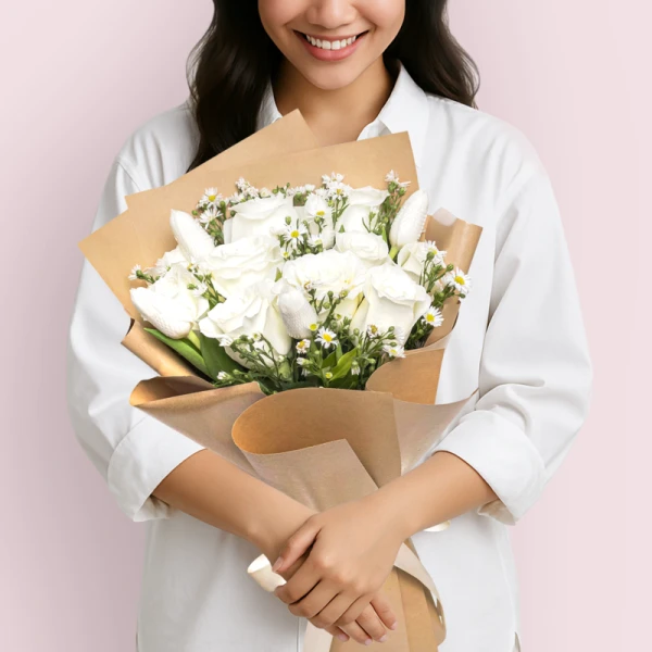 Woman in white shirt holding a bouquet of white roses, tulips, and asters.