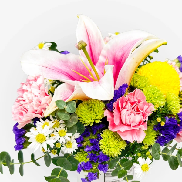 Pink stargazer lily with yellow, green, and pink flowers, and eucalyptus leaves.