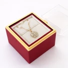Gold rose necklace with pearls inside a red jewelry box with a clear lid.