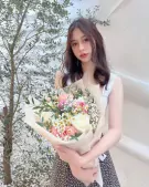 Woman holding a bouquet of pink and white roses, daisies, and baby's breath.
