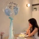 24" bubble balloon with "Happy B Day" text, filled with blue and white mini balloons and light blue tassels.