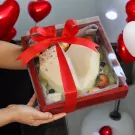 White heart-shaped chocolate cake with fruits and Ferrero Rochers in a red gift box.