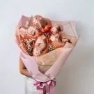 Rose gold heart-shaped balloons and white baby's breath in a pink bouquet, tied with a pink ribbon.