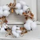 Cotton Flower Mistletoe wreath with cinnamon sticks and twine on a white background.