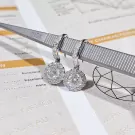 Round-cut moissanite diamond halo dangle earrings on tweezers with gemological report.