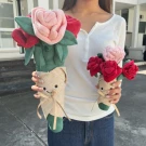 Plushy red roses bouquet with a smiling face on the pot, held by a person.