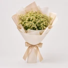 A bouquet of daisies wrapped in kraft paper, tied with twine.