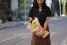 A smiling person holds a graduation bouquet with daisies, ping pong mums, and a mini graduation cap.