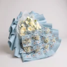 Money bouquet with white roses and baby's breath, wrapped in blue paper.