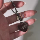 Hand holding a personalized engraved heart keychain with a holographic initial charm.