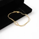 Gold-tone bracelet with infinity knot on double strands, resting on black velvet.