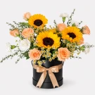Black box with sunflowers, pink roses, and white carnations.