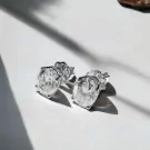 Pair of oval-cut moissanite diamond earrings with silver settings on a white surface.