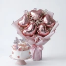 Rose gold heart balloons and a white butterfly cake on a pink stand.