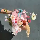 Pink butterfly bloom box with assorted artificial flowers and a ribbon handle.