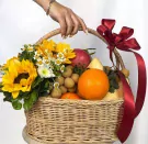 A fruit basket with sunflowers, daisies, oranges, apples, and longans, tied with a red ribbon.
