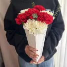 A bouquet of red and white carnations in a white cone holder.