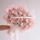 Money bouquet with pink paper, white flowers, and a pink ribbon.