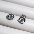 Pair of 0.5-carat round-cut moissanite diamond earrings set in silver with a white textured background.