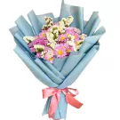 Bouquet of pink-purple mums and white statice in blue paper, tied with a pink ribbon.