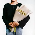 A person holds a bouquet of 22 Ferrero Rocher chocolates wrapped in beige paper.
