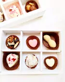 Chocolates in a white box: nuts, pink heart, peanut, strawberry, chunky, white heart.