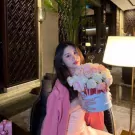 Woman holding a pastel pink and white rose box with a pink ribbon.