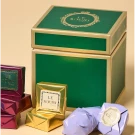 Le Souri Christmas Chocolate Box with gold, maroon, and lavender chocolates and a green and gold gift box.