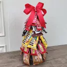Chocolate Christmas tree made of candy bars and M&Ms, topped with a red bow.