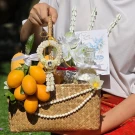 Songkran gift basket with golden fruits, faux jasmine garland, flowers, and traditional items.
