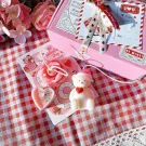 Valentine's Day teddy bear and rose candles on a pink box and red gingham.