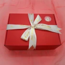 Red gift box with white ribbon and gold hearts, a "Valentine's Day" sticker with a bear.