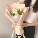 White tulips in a light pink bouquet with a yellow ribbon.