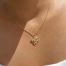 Close-up of a gold necklace with a translucent, four-leaf clover-shaped pendant with yellow accents.