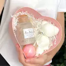 Pink heart-shaped box with bath bomb, rose bath salts, and a white teddy bear towel.