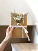Gift-wrapped "Good Vibes, Good Life" book adorned with dried baby's breath and white ribbon.