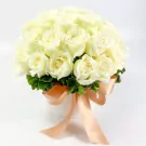A round white box filled with 25 white roses, adorned with a peach ribbon.