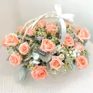 A woven basket overflowing with soft pink roses, baby's breath, and daisies, tied with a white ribbon.